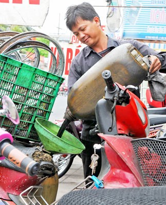The filed photo shows a man collecting used engine oil (Photo: SGGP)